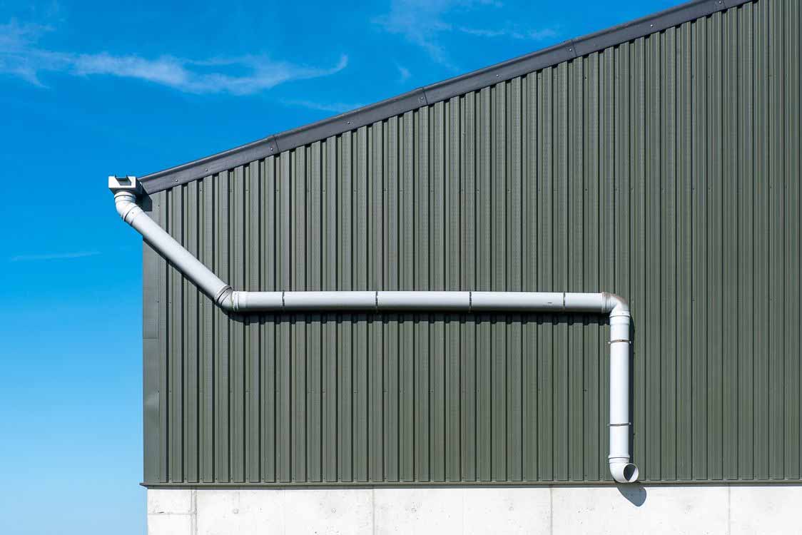 Rainwater downpipe and gutter system fixed to a modern building exterior for roof water collection